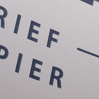 Detailaufnahme von bedrucktem Briefpapier in DIN lang auf Leinenstrukturpapier