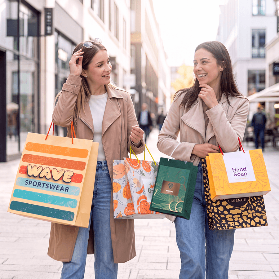 Zwei Frauen tragen beim Shoppen bedruckte Papiertragetaschen mit PP-Kordeln