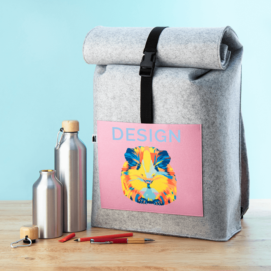 Grauer Rolltop-Rucksack aus Filz, individuell bedruckt auf Vordertasche, daneben Flaschen und Stifte