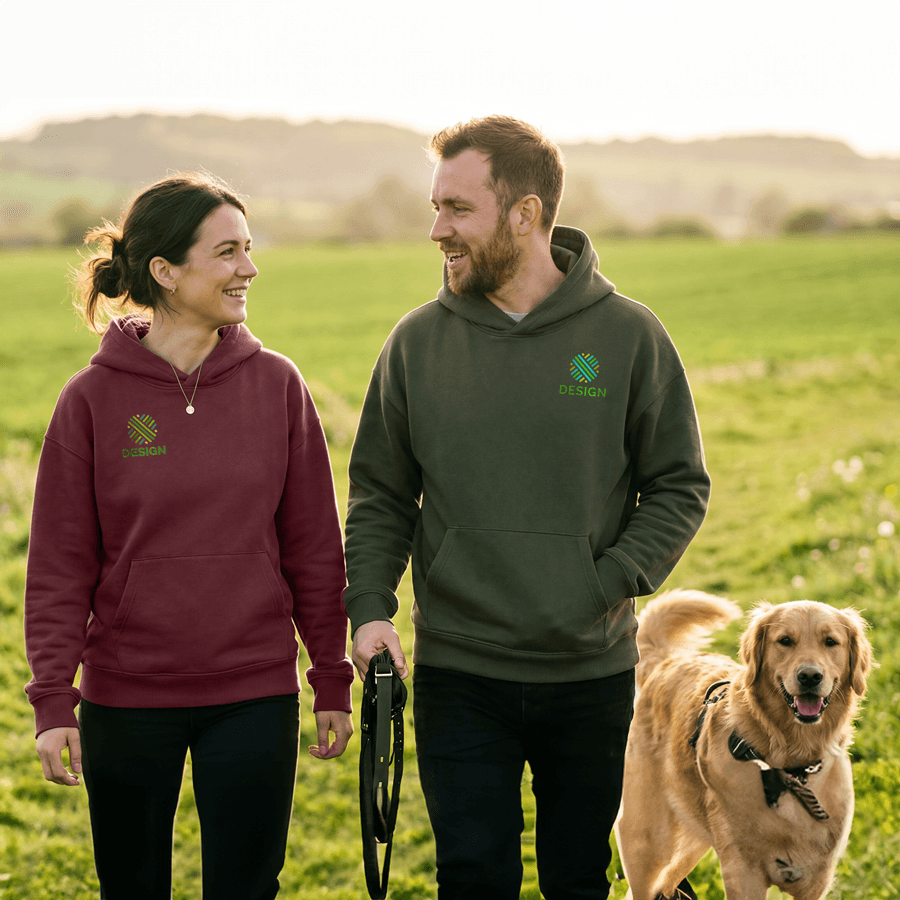 Ein Paar in bedruckten Stanley/Stella-Hoodies geht mit seinem Hund spazieren